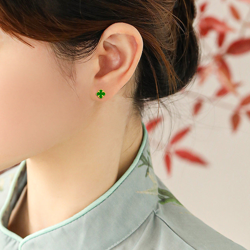 Minimalist profile view of a model wearing the solid green jadeite clover statement stud earring on the ear lobe.