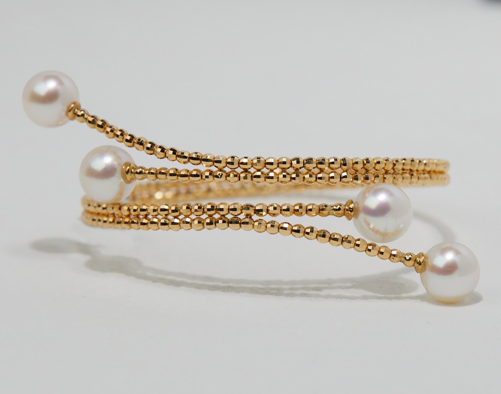 BoxUnboxed 18K yellow gold multi-coil spiral bangle with four Akoya pearls and diamond-faceted beads.