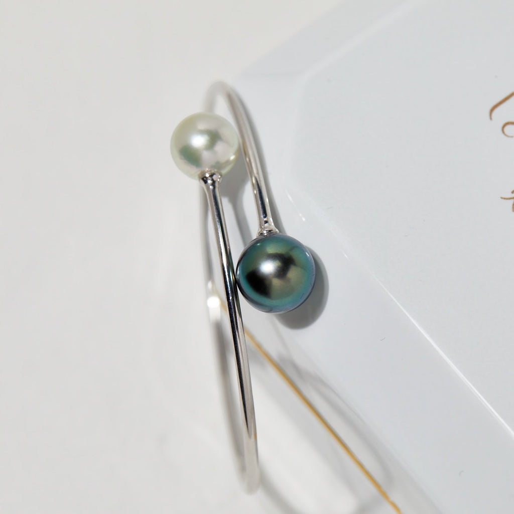 BoxUnboxed 18K white gold bypass bangle with a white Akoya pearl and a dark Tahitian pearl.