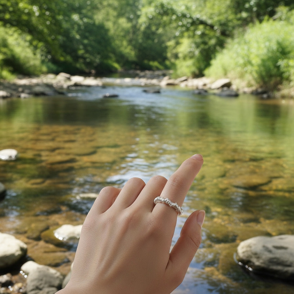 BoxUnboxed sterling silver coiled ring with a baroque pearl accent on a finger, styled with a cup of tea and notebook.