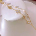 BoxUnboxed double-layer gold bracelet with white pearls and clover charms. Features gold-plated finish, freshwater pearls, and clover motifs.