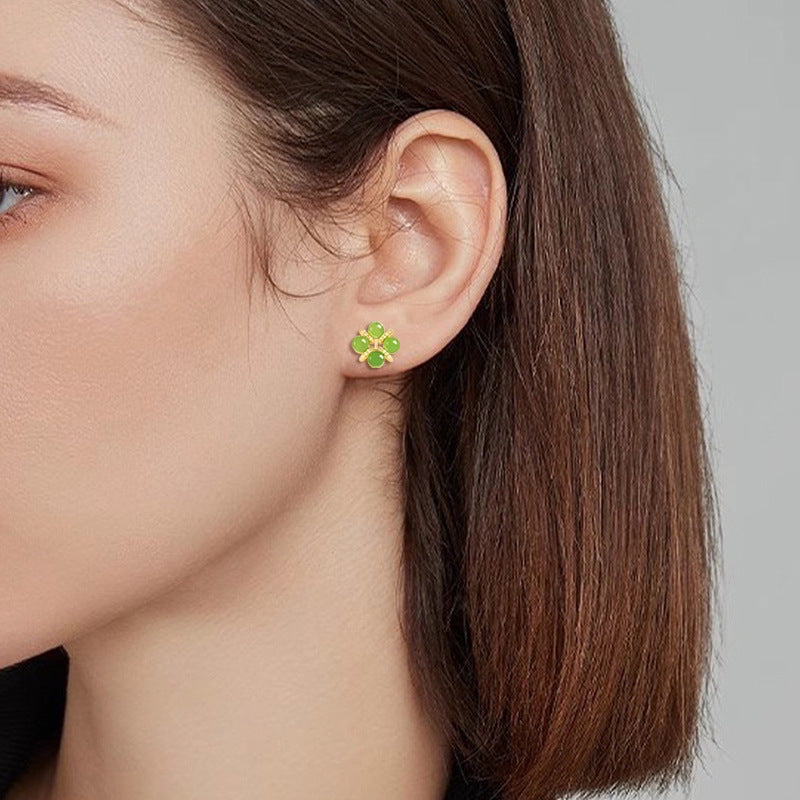 BoxUnboxed four-leaf clover stud earrings featuring green jadeite cabochons set in gold vermeil on a model's ear.