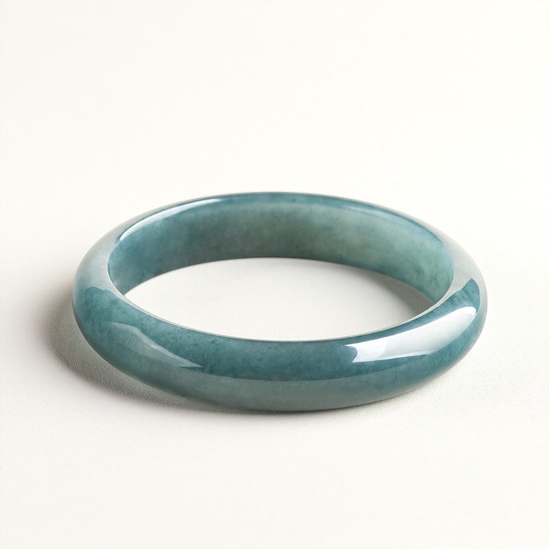 BoxUnboxed Meridian Natural Blue Water Jadeite Bangle, a unisex bracelet with a deep ocean-teal hue and smooth, rounded profile.